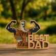 A1 Egy 5 rétegű, 3D hatású testépítő apa dísz, amely egy súlyzózó apát ábrázol hegyvidéki tájjal, "BEST DAD" felirattal. A testépítő apa dísz piros háttéren fekszik.