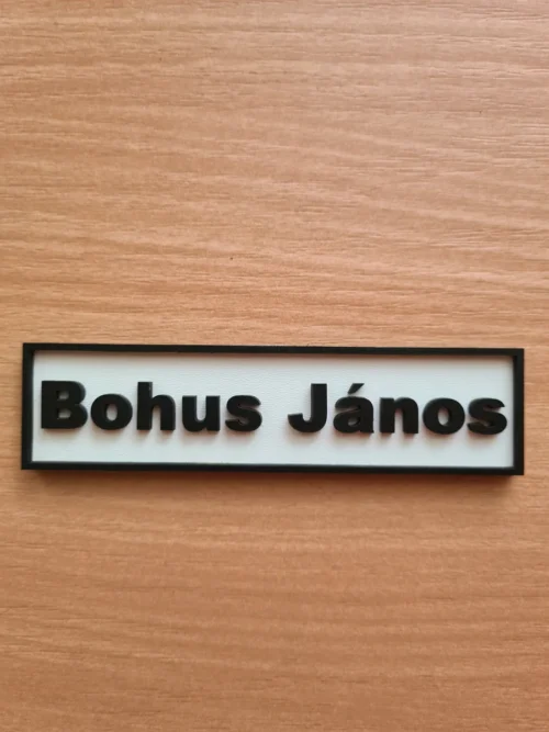 20250801_170813_result_result Fehér alapon fekete betűkkel és kerettel készült, rétegelt, 3D hatású névtábla ajtóra.