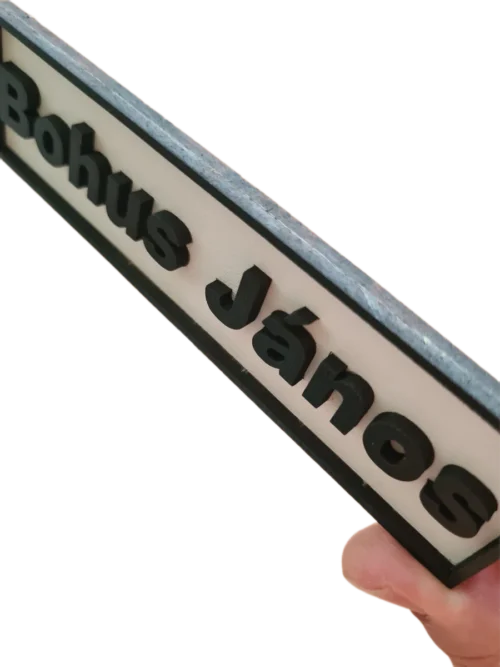 snapedit_1754061664359_result Fehér alapon fekete betűkkel és kerettel készült, rétegelt, 3D hatású névtábla ajtóra. felül nézet