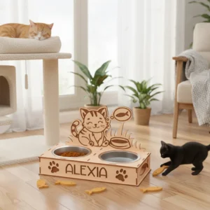 Cuki cicás etetőtál az "Alexia" névvel gravírozva, egy nappaliban, mellette egy fekete kiscicával.