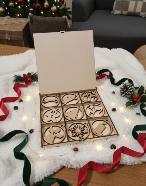 nyitott doboz Nyitott karácsonyi díszdoboz 9 db fa dísszel, egy fehér szőrmén, ünnepi fényekkel körbevéve.