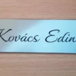 Ezüst 1 név középen. írott betűvel_result Ezüst színű ajtónévtábla kézírásos betűtípussal, "Kovács Edina" névvel gravírozva.