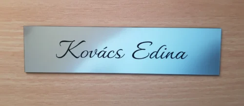 Ezüst 1 név középen. írott betűvel_result Ezüst színű ajtónévtábla kézírásos betűtípussal, "Kovács Edina" névvel gravírozva.