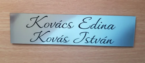 Ezüst-2 soros névtábla-írott betűvel_result Kétsoros, kézírásos betűs ezüst ajtónévtábla "Kovács Edina" és "Kovács István" nevekkel.