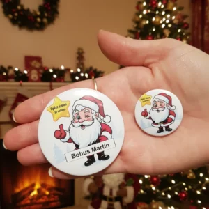 Stock kéz_result Két különböző méretű, névre szóló mikulás kitűző egy női kézben, karácsonyi háttérrel.