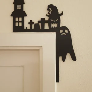 Fekete halloweeni dekoráció egy ajtó sarkán, amely egy kísértetkastélyt és egy szellemet ábrázol.