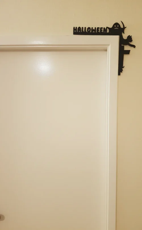 ajtódíszfeketemacslás_result Fekete "HALLOWEEN" feliratú sarokdísz egy ajtókereten, egy macskával és egy szellemmel.