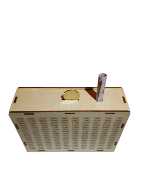 Persely-felünézet Fa persely felülnézete a bedobónyílásokkal, egy 200 forintos érmével és egy feltekert papírpénzzel a számhálós oldal felől.